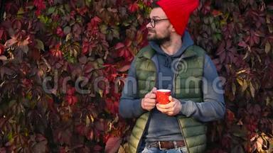 戴着红帽子的人手里拿着一个杯子在<strong>户外喝茶</strong>或咖啡。 咖啡时间。