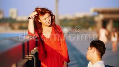 夏天的夜晚，红头发的女孩和坐在轮椅上的男人在海滨聊天