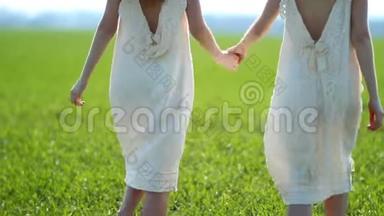 在一个阳光明媚的日子里，两个穿着白色亚麻衣服的女孩沿着农村的一片绿色草地散步。 <strong>身体部位</strong>