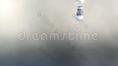 一滴纯净的水从融化冰柱的顶部滴下来。