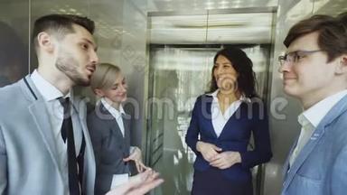 跟踪女商人和女商人同事在移动<strong>电梯</strong>中交谈的镜头，然后从<strong>电梯</strong>里出来，走进来