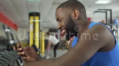 健身俱乐部成功的微笑运动员在智能手机上<strong>滚动照片</strong>