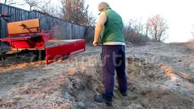 男人用铲子把沙子装进摩托车的拖车里
