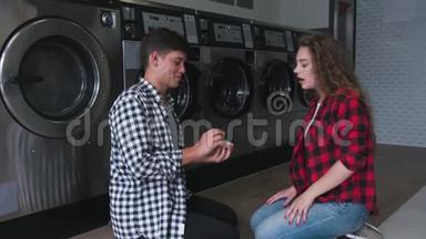 穿衬衫的帅哥在洗衣店向红卷发女人求婚。 她答应了