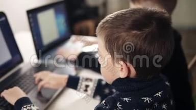 两个男孩学习如何使用笔记本电脑的背面镜头。 编程课。 教育过程。