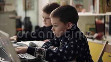 两个穿着温暖舒适毛衣的小男孩坐在笔记本电脑前的编程<strong>课</strong>上，<strong>试</strong>图慢镜头