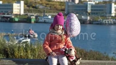 小女孩带着<strong>气球坐</strong>在河港上，一边旅行，一边微笑