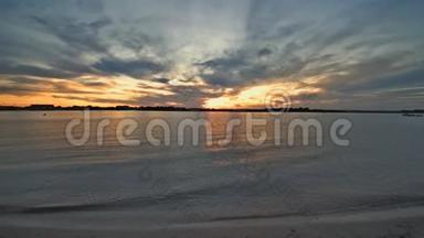 空中无人驾驶飞机在夕阳的天空下，在浅沙的海面上飞行