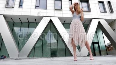 夏天，红头发的女人对着镜头对着背景模糊的公司大楼摆姿势