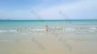 年轻女子穿着比基尼在蓝色的海洋天际线背景。 在天堂海滩上的绿松石海中的无人机观看女人。