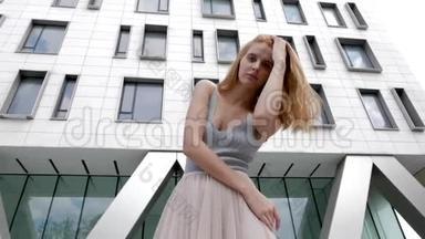 夏天，红头发的女人对着镜头对着背景模糊的公司大楼摆姿势