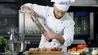 男厨师在专业厨房煮肉。 厨师烹饪牛排的肖像。
