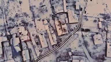 空中无人机镜头低飞，而房子和街道被雪覆盖。