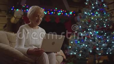 老太太在<strong>圣诞树</strong>旁用笔记本电脑做<strong>视频</strong>翻译