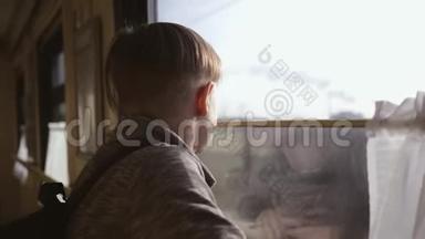 这个男孩站在火车窗口，<strong>看着窗外</strong>的风景。 坐火车旅行。 旅游业