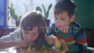 快餐，孩子们在午餐时吃美味的披萨，坐在桌子上，靠在窗户上