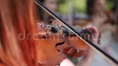 女孩手拉小提琴的特写。 在外面听音乐。 婚礼仪式