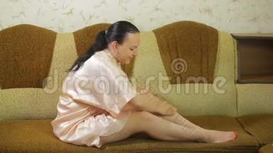 沙发上的一位年轻女士脱毛后将滑石粉涂在腿上
