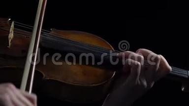 女人在黑暗的房间里拉小提琴弦。黑色背景。闭合