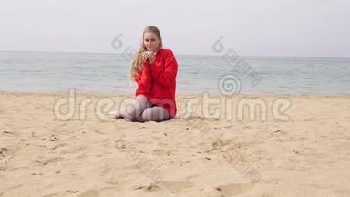 金发女郎坐在海边的沙滩上