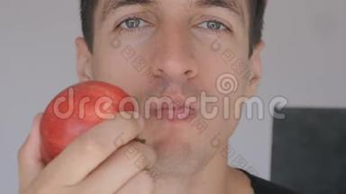 一群年轻人在家里厨房里吃红苹果。 吃新鲜苹果的家伙的画像