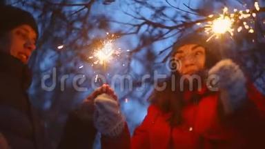 一个男人和一个女孩在冬天的森林里点燃圣诞节的火花。