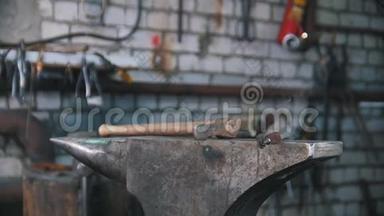 一把钳子和一把锤子放在铁砧上。 铁匠工作室。