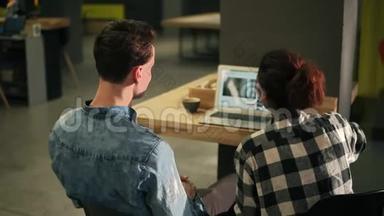 一对夫妇坐在一个光线充足的室内空间，使用笔记本<strong>电脑</strong>的<strong>背面</strong>镜头。 上网，看一些视频
