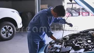 年轻的亚洲<strong>汽车</strong>机械师在<strong>汽车</strong>修理车间的<strong>汽车</strong>引擎盖检查发动机。 维修人员检查客户安全