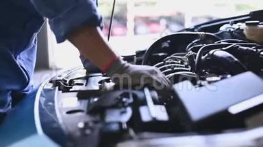 年轻的亚洲汽车机械师在汽车修理车间的汽车引擎盖检查发动机。 维修人员检查客户安全