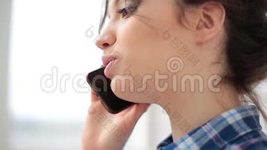 迷人而开朗的年轻女人在室内使用手机。 她在电话里说着笑。 快关门。