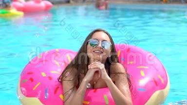 夏天美丽的年轻女子。 比基尼女孩哈文在洒满甜甜圈的乐趣在游泳池，假期，夏天，夏天