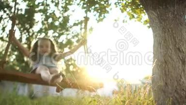 一个赤脚的女孩骑在夕阳的光<strong>线下</strong>的木秋千上。 底部视图，特写