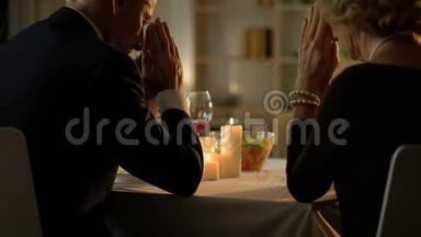 <strong>老夫妻</strong>饭前祈祷，坐在餐桌前，吃感恩节晚餐