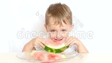 一个快乐的孩子坐在一张桌子旁，吃着白色背景的西瓜，吃着一顿快乐的饭。