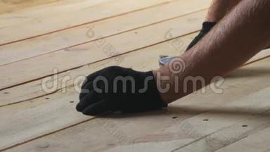 一个人用钉子钉在木板上的特写镜头。 工人用钉子和锤子的细节。