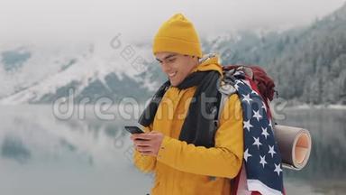 美国旅行者在徒步冬<strong>季</strong>旅行中使用智能<strong>手机</strong>。 白雪皑皑的湖面和背景下的群山。 旅行和
