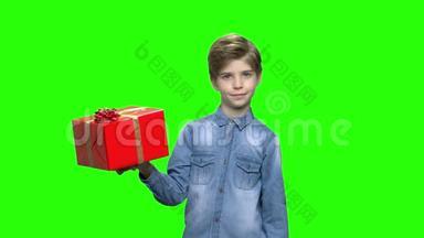 可爱的男孩指着红色的礼盒。
