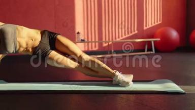 女人在蓝色<strong>垫子</strong>上做腹部锻炼的侧木板。 关于健身的视频