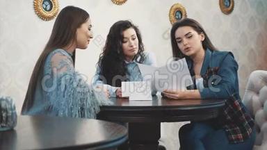 快乐的三个漂亮女孩和她们的女朋友坐<strong>在</strong>咖啡馆里。 <strong>在此</strong>期间，讲述和讲述各种故事