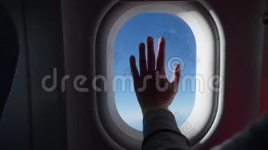 女人的剪影把飞机的窗户递给我。 从飞机、飞机的窗户看到的云彩和天空