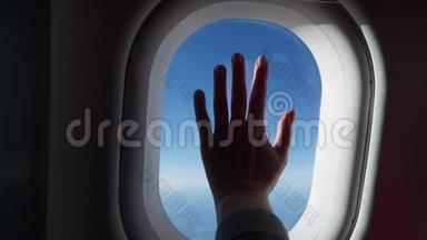女人的剪影把飞机的窗户递给我。 从飞机、飞机的窗户看到的云彩和天空