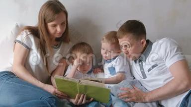 一家人的爸爸妈妈和两个双胞胎兄弟躺在床上看书。 家庭阅读时间。