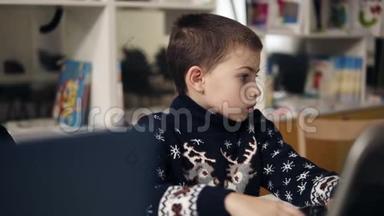 一个小男孩坐在笔记本电脑屏幕前的蓝色大眼睛肖像的慢镜头。 编程课