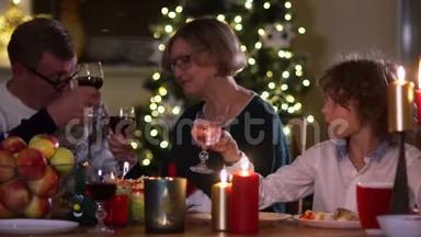 大家庭聚集在圣诞餐桌前，一家人聚餐.. 大人从杯子里喝红酒，男孩喝水