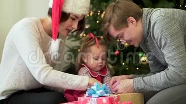 幸福的家庭，父母在圣诞树前向他们可爱的孩子展示新年装<strong>饰品</strong>。 妈妈<strong>戴</strong>着圣诞帽