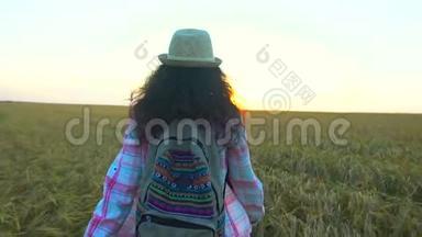 <strong>夏日</strong>夕阳下，女游客漫步麦田。 徒步旅行者女人戴着<strong>帽子</strong>，背着背包徒步旅行。 女孩