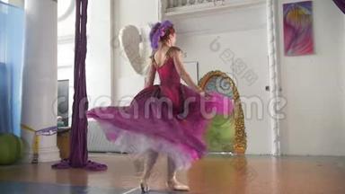 年轻漂亮的穿着紫色衣服的芭蕾舞女演员在宽敞的白色<strong>工作室</strong>里表演<strong>舞蹈</strong>