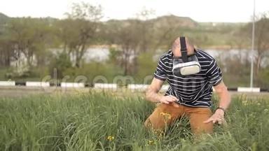 一个戴着虚拟现实头盔坐在草坪上的人。 潜水游戏或全景视频-周围的电影，和