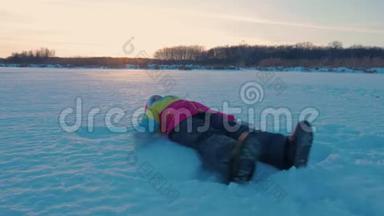 快乐的女孩躺在雪地上展示天使。 一个穿外套的漂亮女孩躺在雪地上，张开双臂。